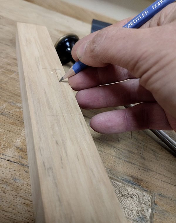 Renforcement des tracés du trusquin avec un crayon sur la pièce de bois