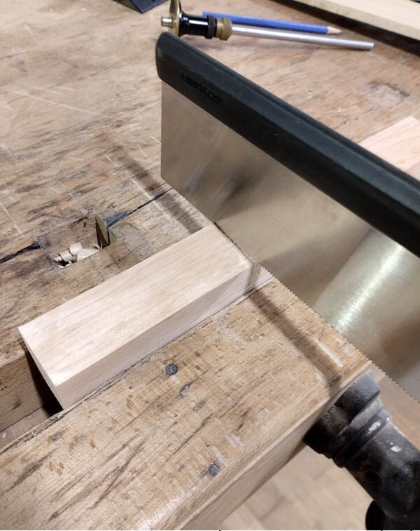 Sciage des limites de l’entaille sur la pièce serrée dans la presse à l’aide d’une scie à dos.