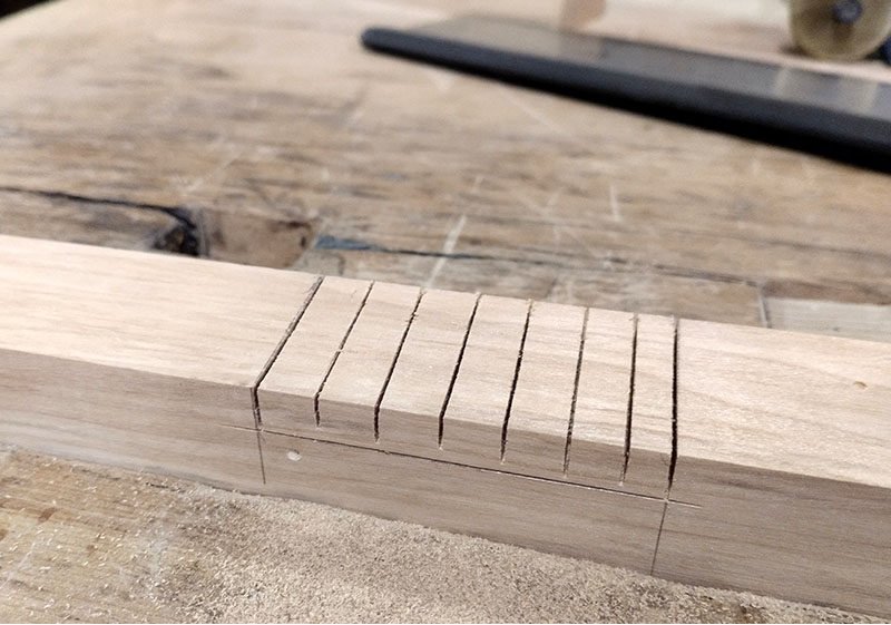 Pièce serrée dans la presse avec traits de scie pour faciliter le retrait du bois